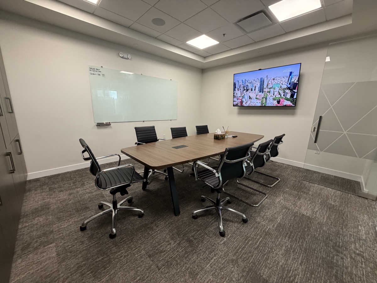 10-person boardroom in Unit B500 with conference table, wall-mounted display, and whiteboard